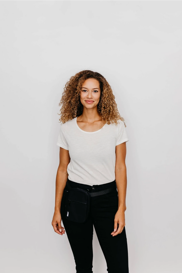 Woman with white shirt and black pants wearing crossbody sling as kip pack. 