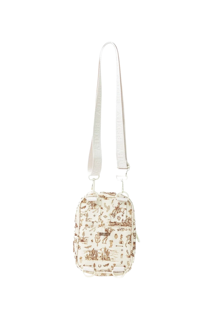 A small crossbody bag with a cream-colored fabric body featuring a brown desert scenery, complete with a matching cream-colored shoulder strap.