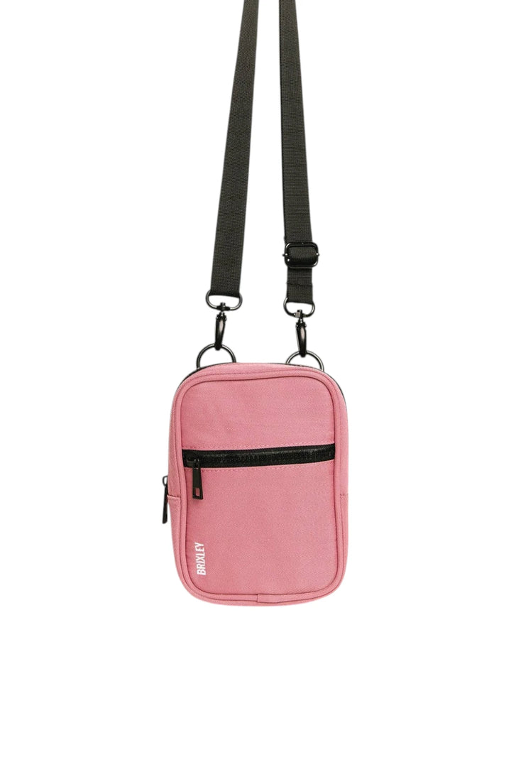 A pink crossbody phone bag with a black adjustable strap and black zipper details, shown against a plain white background.