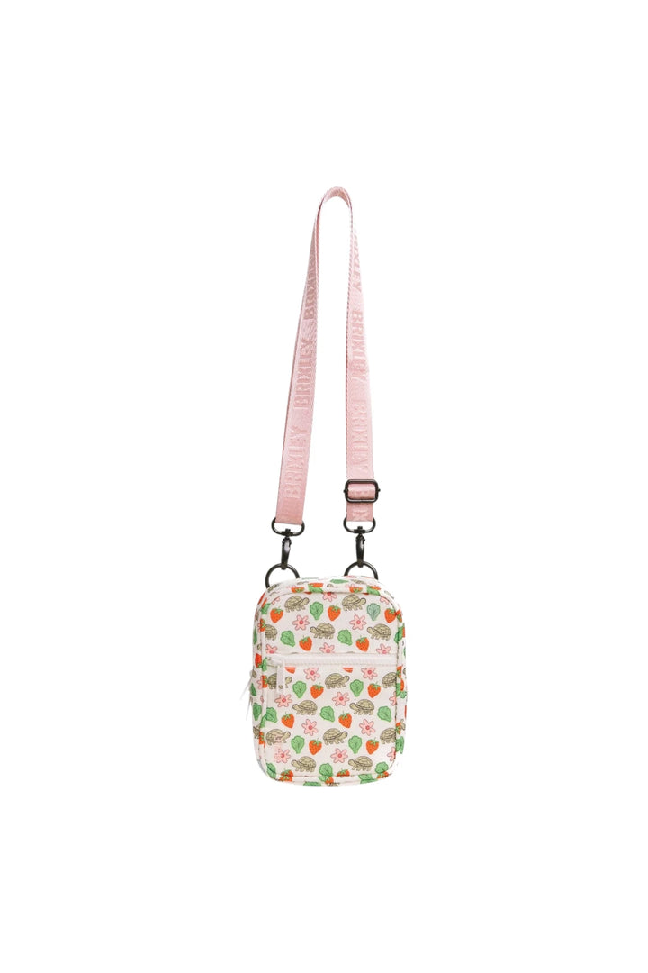 A small crossbody bag with a pink strap and a white body covered in a strawberry and green leaf pattern, shown against a plain white background.