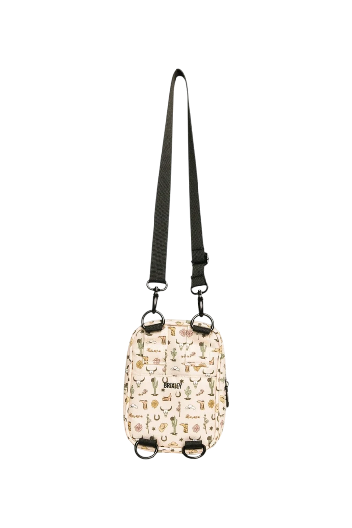 A small crossbody bag with a cream background and a multicolor western pattern, featuring a black adjustable shoulder strap and black hardware, shown against a plain white background.