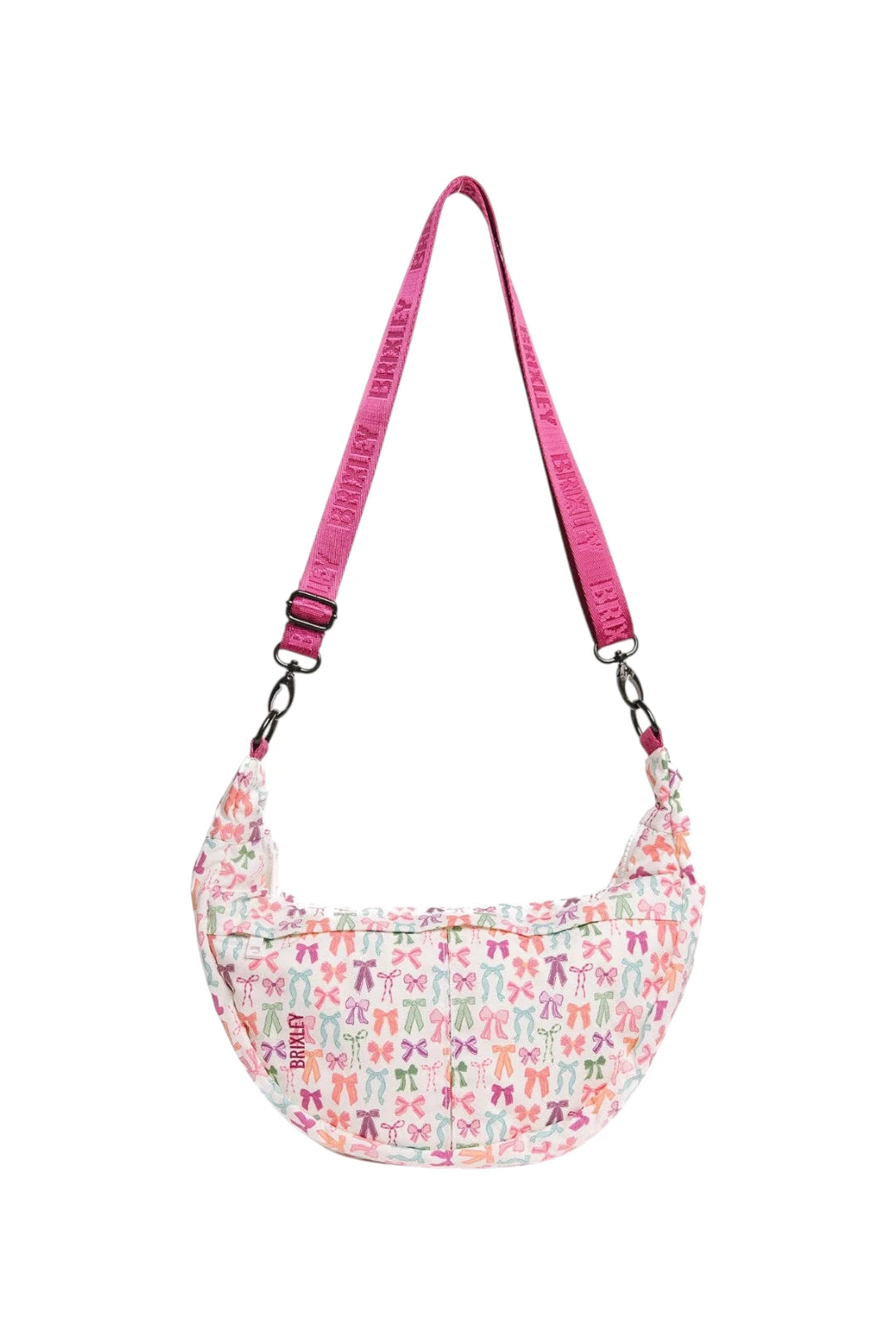 A crescent-shaped shoulder bag with a white background covered in a colorful pattern of bow ties, featuring a bright pink adjustable strap with 'BRIXLEY' printed repeatedly.