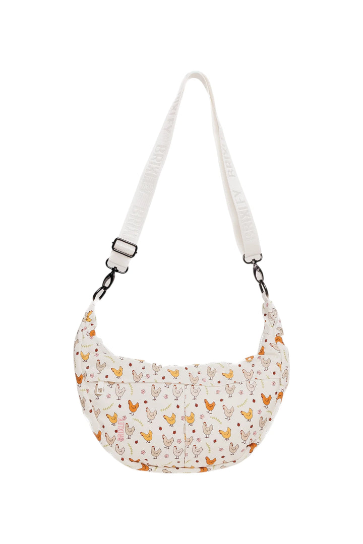 A crescent-shaped shoulder bag with a white strap and a white fabric body covered in a colorful pattern of chickens, shown on a plain white background.