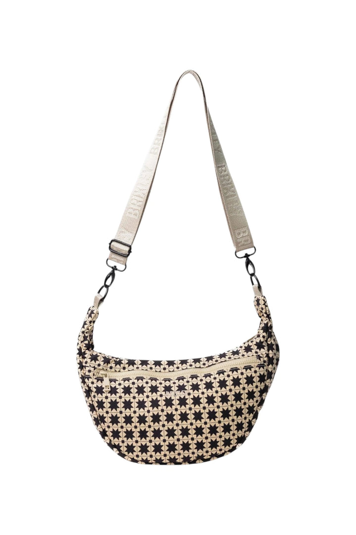 A small crescent-shaped shoulder bag with a black and beige geometric star pattern, featuring a matching beige adjustable shoulder strap with white text, shown on a plain white background.