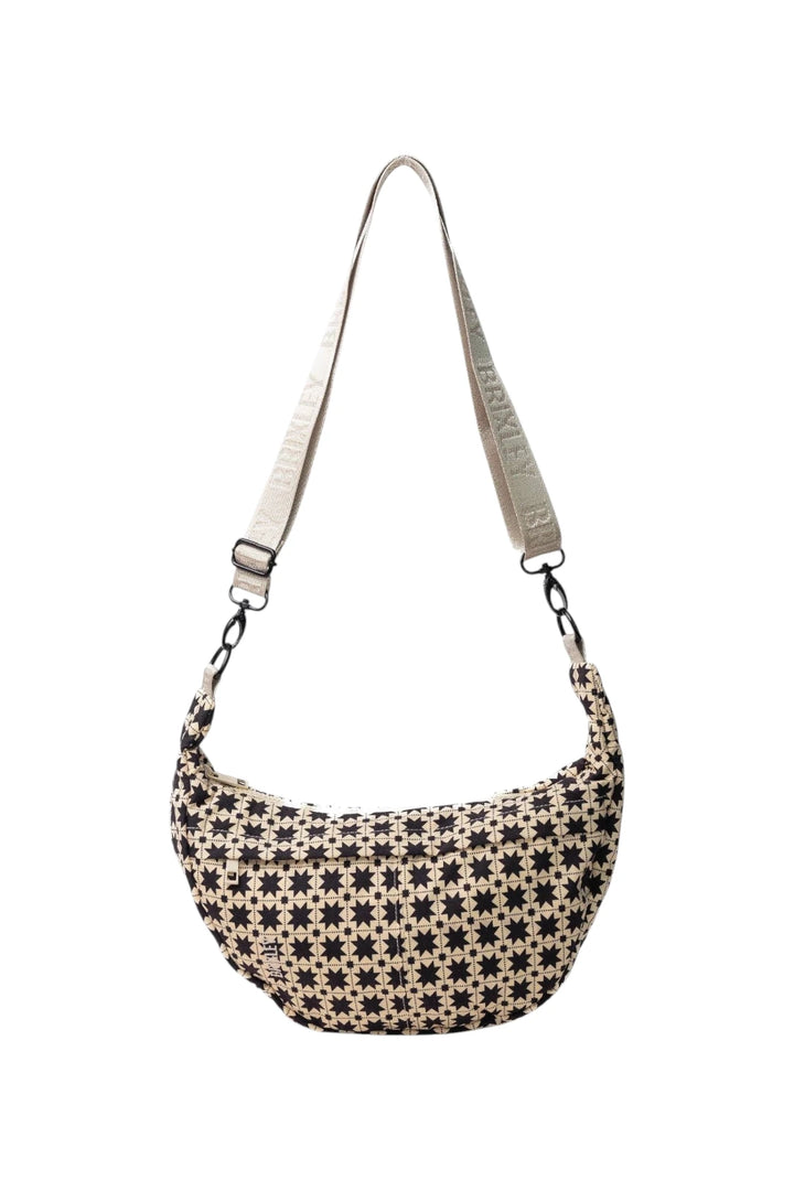A crescent-shaped shoulder bag with a black and beige geometric star pattern, featuring a light beige adjustable shoulder strap with 'BRIXLEY' printed on it, shown against a plain white background.