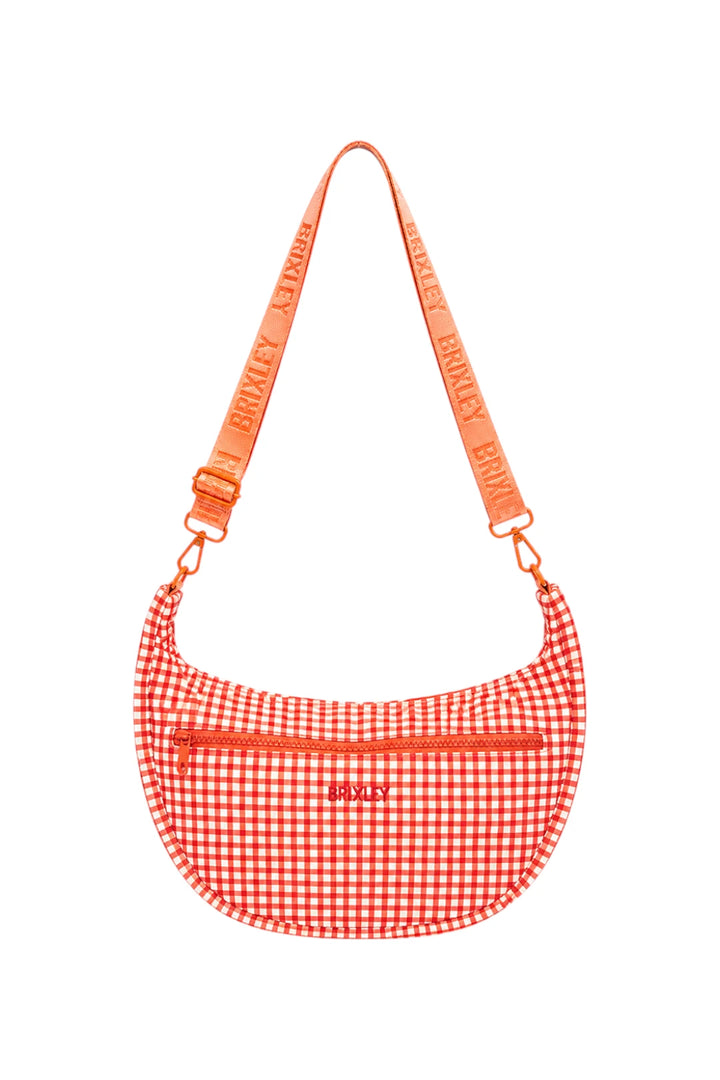 A red and white gingham crescent-shaped shoulder bag with a matching orange-red webbed strap featuring the brand name 'BRIXLEY' repeated, shown on a plain white background.