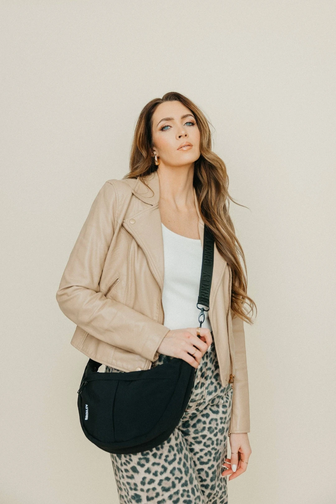Woman wearing a black crossbody bag against a plain background