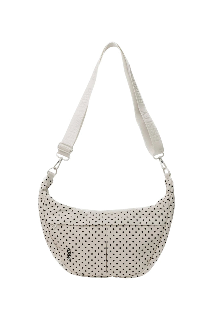 A white crescent-shaped shoulder bag with black polka dots and a matching white adjustable shoulder strap, shown against a plain white background.
