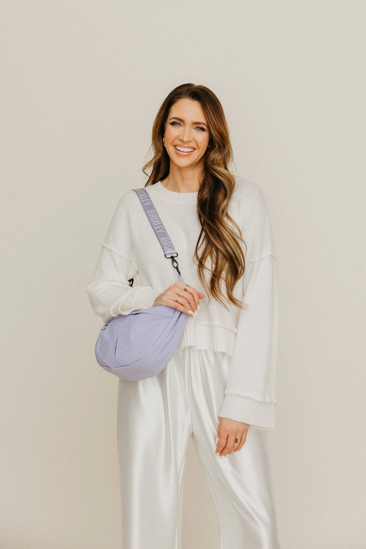 Woman holding a purple bag against a plain background
