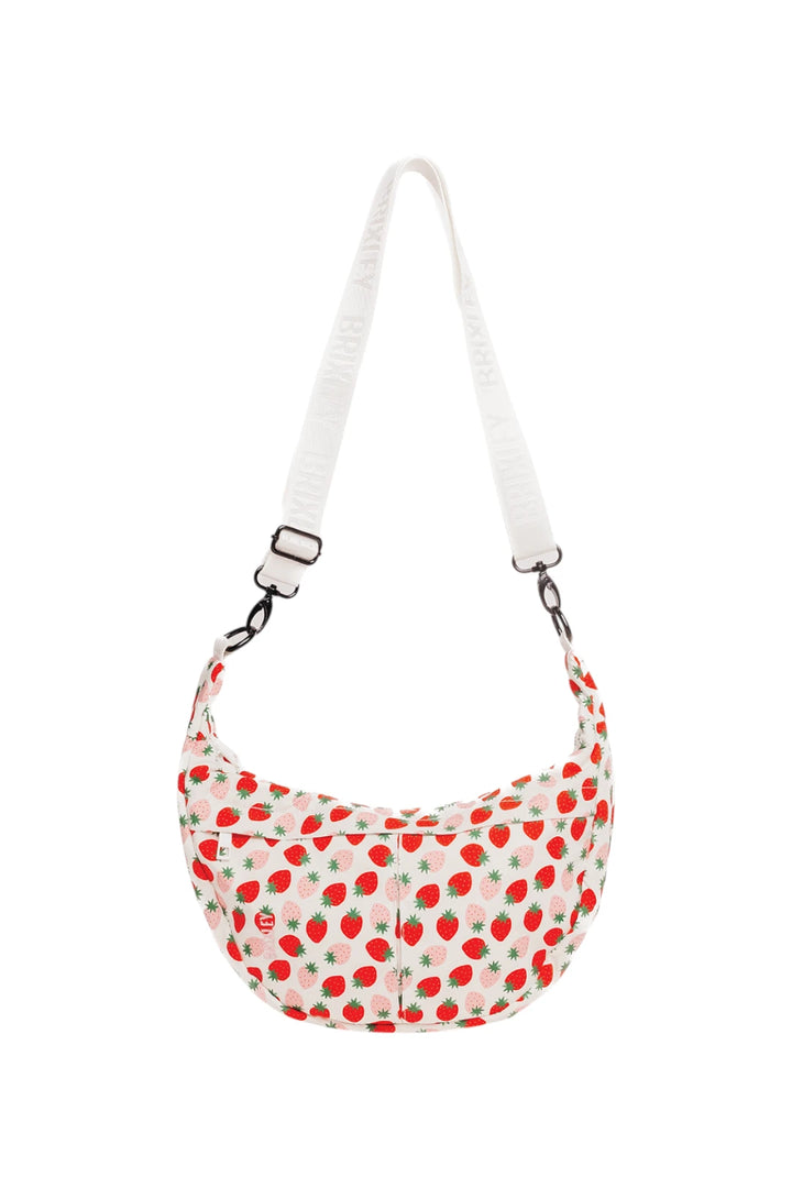A crescent-shaped shoulder bag with a white strap, featuring a red strawberry pattern on a white fabric body with small green leaf accents.