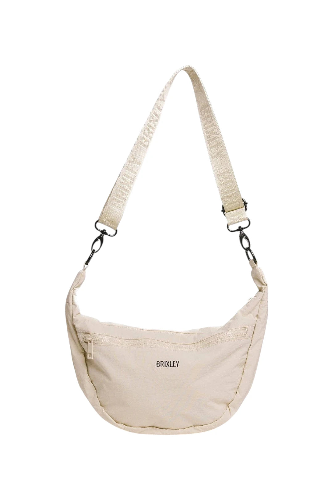 A cream-colored crescent-shaped crossbody bag by BRIXLEY, featuring a matching branded webbing strap and black hardware, shown against a plain white background.