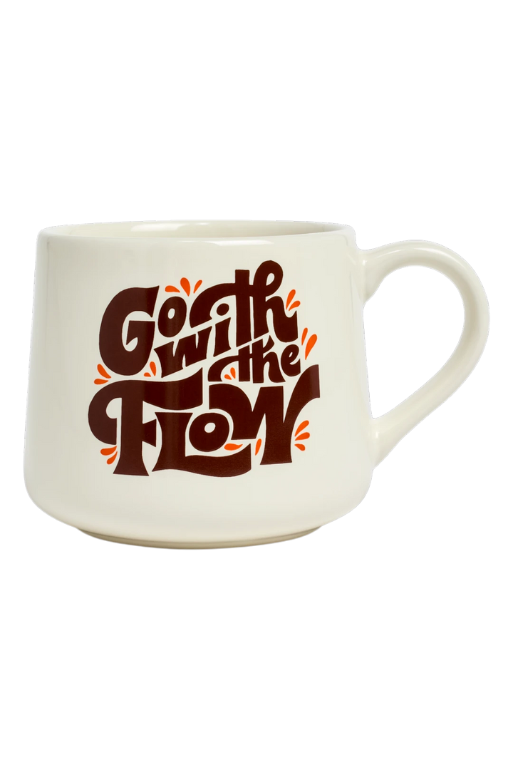 An off-white ceramic coffee mug featuring a retro-style graphic that reads 'Go with the flow' in dark brown lettering with orange paint splatters, set against a plain white background.