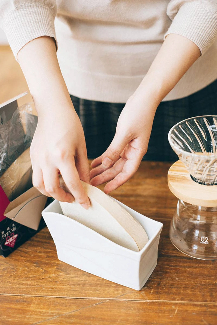 Image of person storing V60 filters in paper stand. 